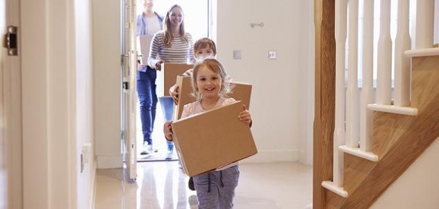 family carrying boxes into new home