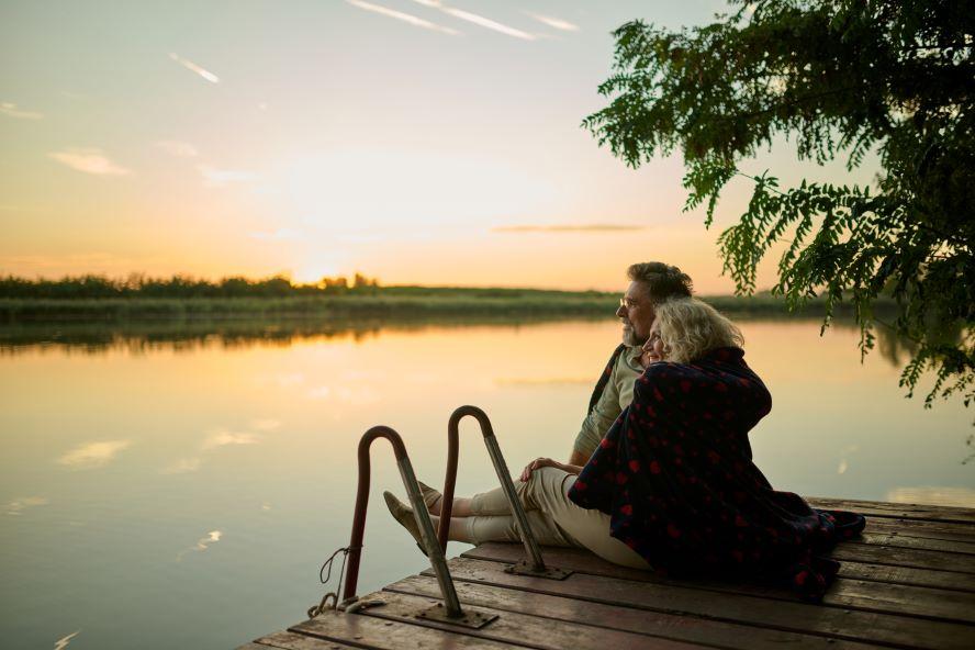 Couple sitting on lake dock at sunset