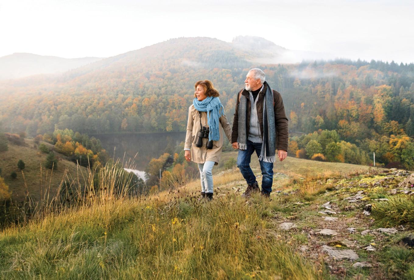 Senior couple walking on hilltop in fall
