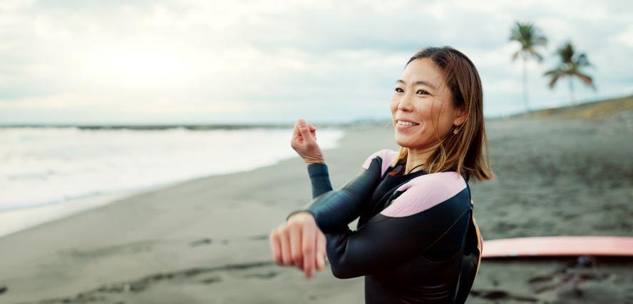 Woman surfer on beach stretching