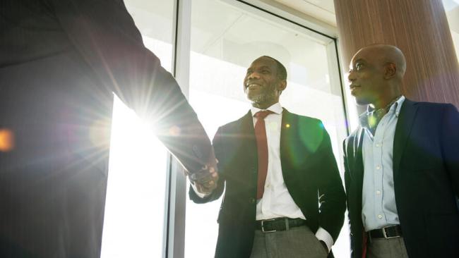 Business men shaking hands with sunlight in window